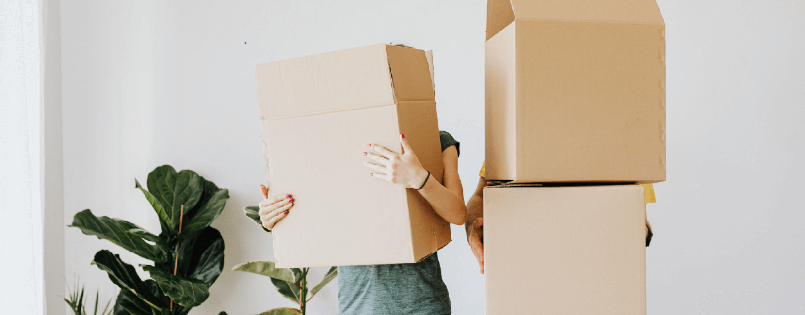 Two unidentifable people carrying moving boxes