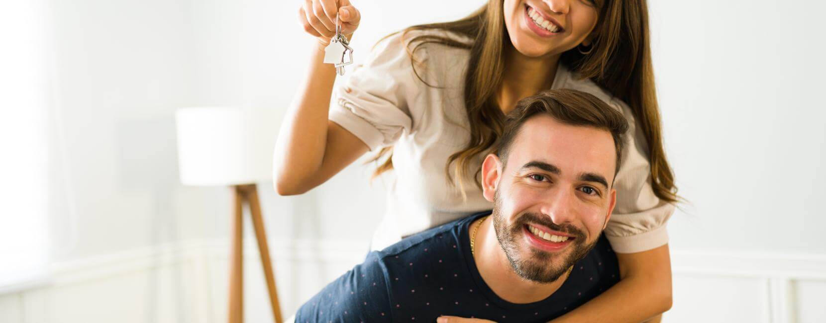 Man and woman showing their new home keys after buying a house