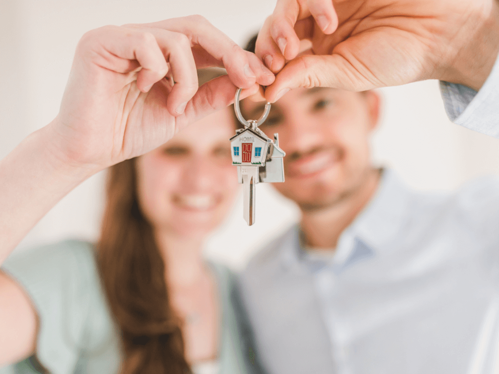 Young couple holding up keys to their new home