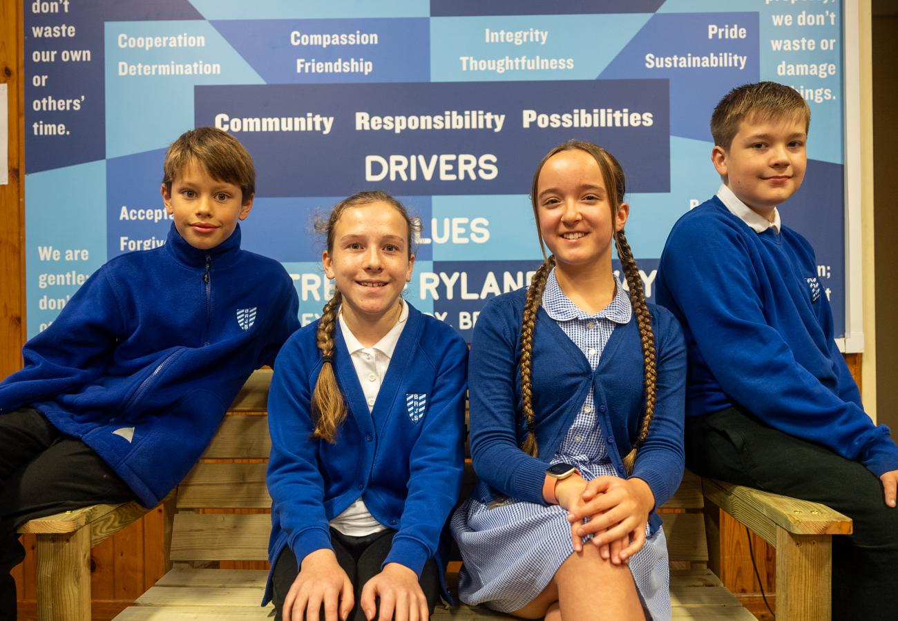 Pupils sitting on buddy bench donation to local school in Beeston